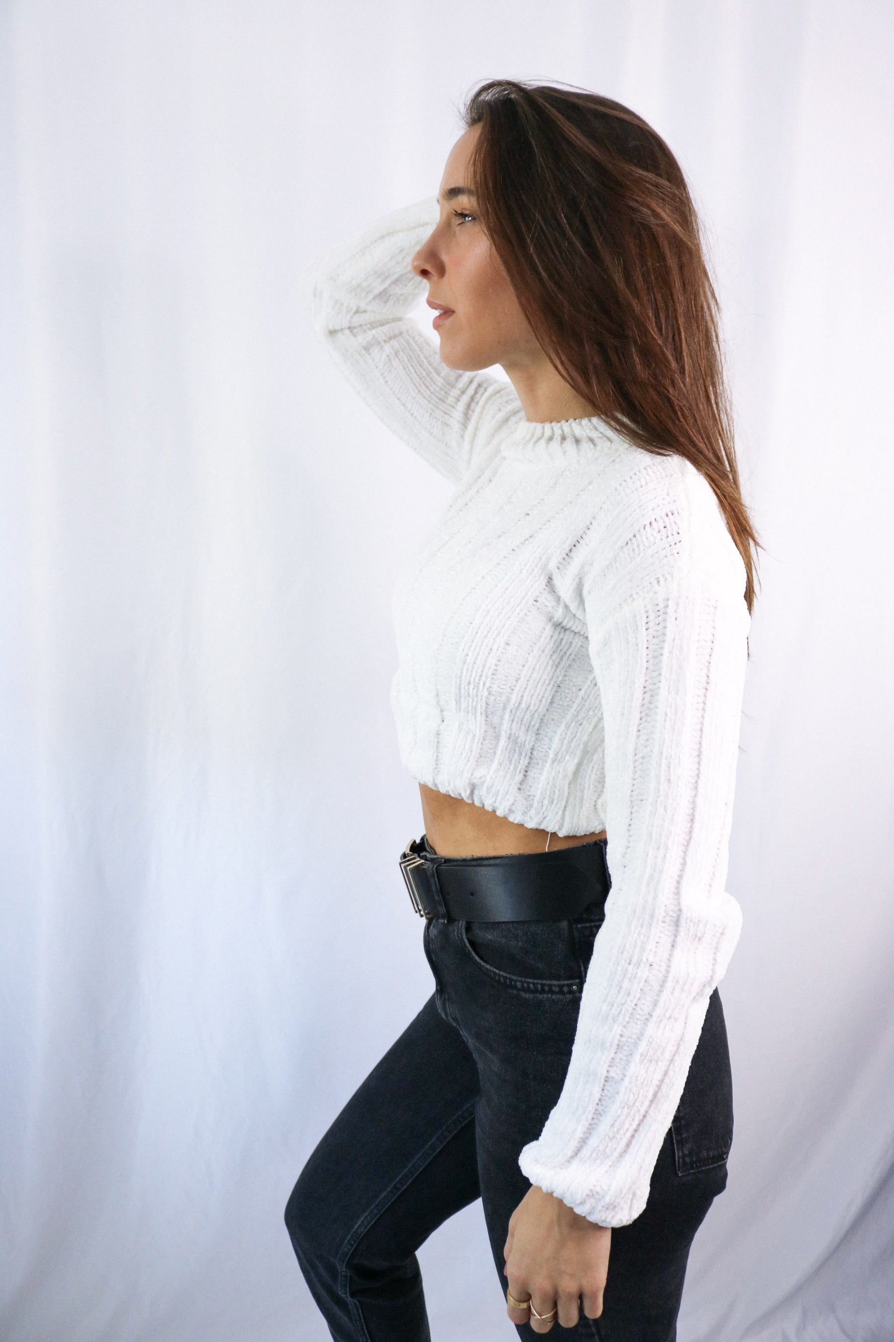 Brunette girl models ivory (white) knitted crop sweater for Scarlette The Label, an online fashion boutique for women. THe knitted crop sweater is very soft and breathable. Paired with dark denim jeans.