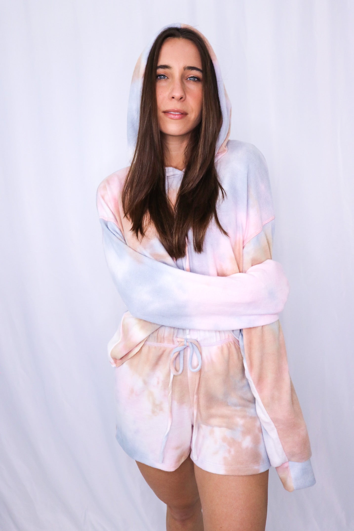 Brunette models long sleeve hoodie tie dye loungewear short set for Scarlette The Label, an online fashion boutique for women.