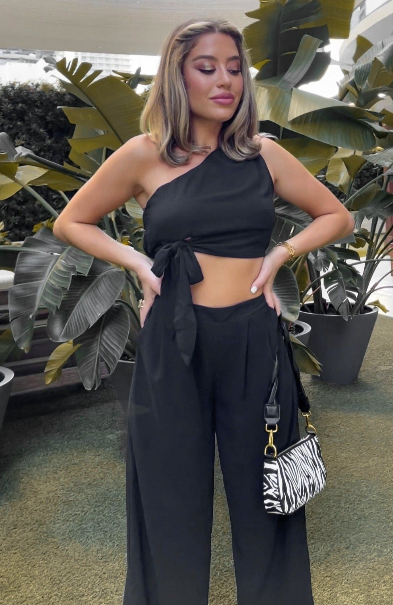 Woven and pleated one shoulder pant set in black with flare pants and side pockets. Scarlette The Label, an online fashion boutique for women.